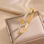 Gold bracelet with diamond accents on a beige fabric background