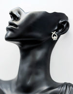 Earring on a black mannequin bust against a white background