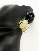 Bold geometric textured gold earrings resting on a display card.