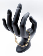 Modeled gold chain bracelet stacked with other jewelry on a woman's wrist.