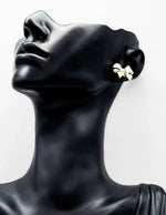Biya Accessoires gold and pearlescent bow stud earrings with crystal center.