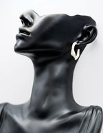 Biya Accessoires gold and cream marbled twisted hoop earrings.