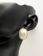 Biya Accessoires gold rim stud earrings with large oval pearl cabochon.