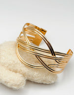 Non-tarnish sculptural overlapping gold bangle for women Dubai luxury fashion.