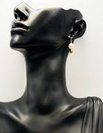 Pearl earring on a black mannequin bust with a white background
