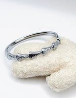 Hypoallergenic non-tarnish high polish silver rigid bangle with pave crystals.
