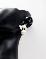 Close up of elegant imitation jewelry uae featuring an enamel ribbon stud and faux pearl drop.