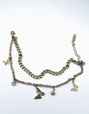 Modeled wrist wearing stacked style non-tarnish gold butterfly charm bracelet for women in UAE.