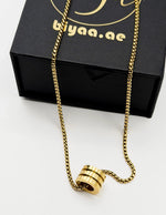 Modern quiet luxury thick gold chain and cylinder pendant Dubai.
