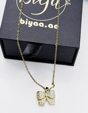 Modern luxury gold and crystal bow statement necklace for women.