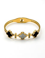 Gold bracelet with clover-shaped charms on a white background