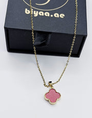 Necklace with a pink clover-shaped pendant in front of a black box with 'biyaa.ae' branding.