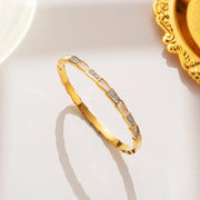 18K gold plated serpentine geometric segmented bangle by Biya Accessoires.