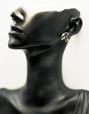Mannequin head wearing a leaf-shaped earring on a white background