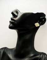 Sparkling crystal knot earrings resting on champagne silk fabric.