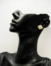 Sparkling crystal knot earrings resting on champagne silk fabric.