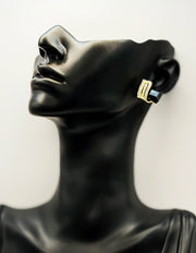 Black mannequin head with gold hoop earrings on a white background