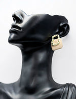 Close up of imitation jewelry uae urban studs featuring textured gold and grid pattern.