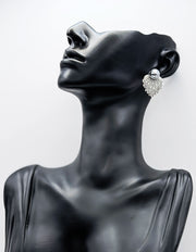 Black mannequin head wearing a sparkling silver earring against a white background
