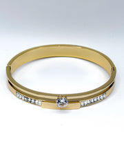 Close up of luxury imitation jewelry featuring a gold cuff with channel-set baguette stones.