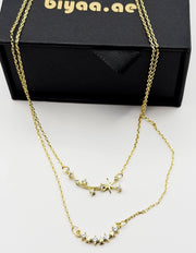 Waterproof and non-tarnish artificial gold double chain necklace resting on silk fabric.