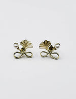 Close up of elegant imitation jewelry uae featuring a golden bow faux pearl and green leaf.