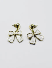 Biya Accessoires gold heart and cream enamel bow drop earrings.