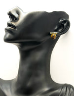 Mannequin head wearing a gold earring on a white background