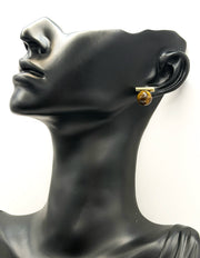 Mannequin head wearing a gold earring on a white background