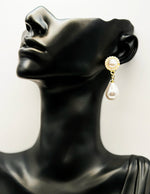 Pearl earring on a black mannequin head against a white background
