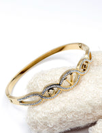 Close up of hinged gold stainless steel jewelry with crystal accents.