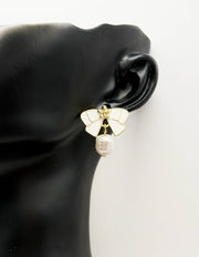 Close up of imitation jewelry uae bow studs featuring golden floral centers and baroque pearls.