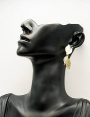 Mannequin wearing a leaf-shaped earring with gold accents on a white background