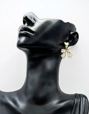 Close up of premium hypoallergenic imitation jewelry featuring a pearlescent bow and gold heart stud.