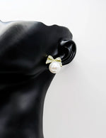 Close up of elegant imitation jewelry uae featuring a pavé crystal bow and faux pearl drop.