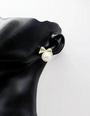 Close up of elegant imitation jewelry uae featuring a pavé crystal bow and faux pearl drop.