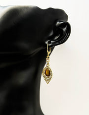 Close up of imitation jewelry uae statement drops featuring pavé frame and amber center.