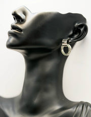 Mannequin head wearing a silver hoop earring with black stones on a white background