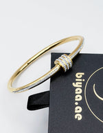 Hypoallergenic gold rigid bangle with cubic zirconia crystals.