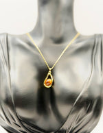 Waterproof gold pear shaped necklace for women on white silk.