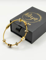 Biya Accessoires 18K gold twisted cable bangle with enamel hearts.