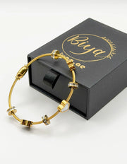 Biya Accessoires 18K gold twisted cable bangle with enamel hearts.