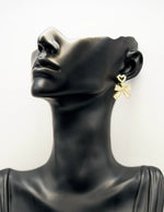 Close up of elegant imitation jewelry uae featuring a pearl heart stud and cream ribbon drop.