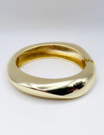 Gold bracelet on a light gray background