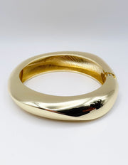 Gold bracelet on a light gray background
