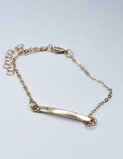 Gold bracelet with a bar clasp on a light gray background