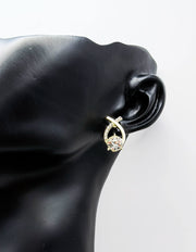 Gold earring with a diamond on a black mannequin ear against a white background