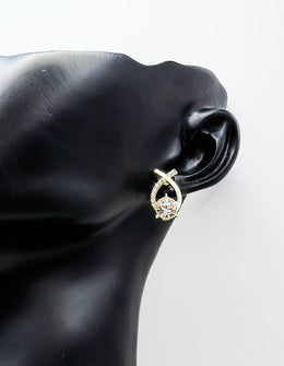 Gold earring with a diamond on a black mannequin ear against a white background