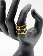 Gold ring on a black mannequin hand against a white background
