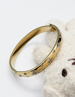 Hypoallergenic non-tarnish high polish gold domed bangle with cubic zirconia.